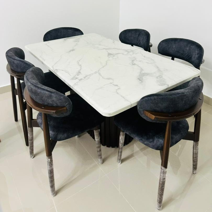 Dining table set with marble top and dark chairs in a room.