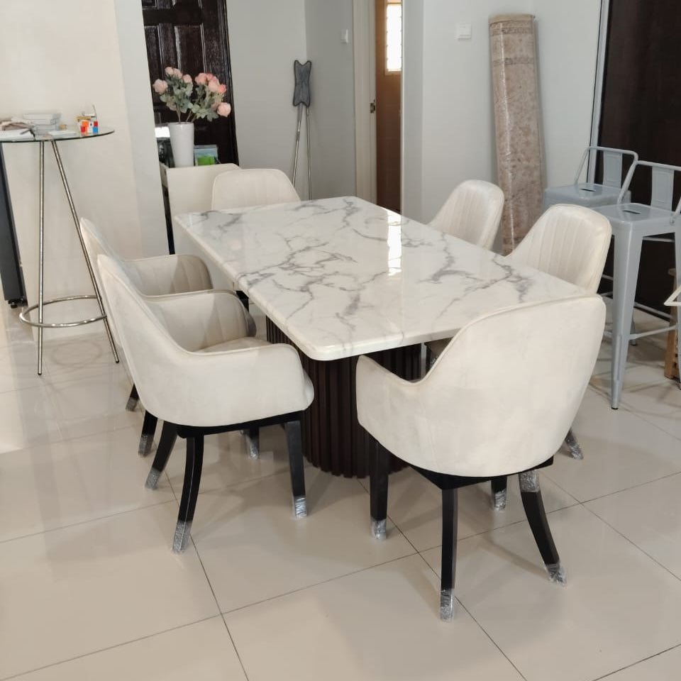 A modern dining set featuring a rectangular white marble-patterned table with a dark wood base and six upholstered cream chairs with black legs, shown in a home interior setting.