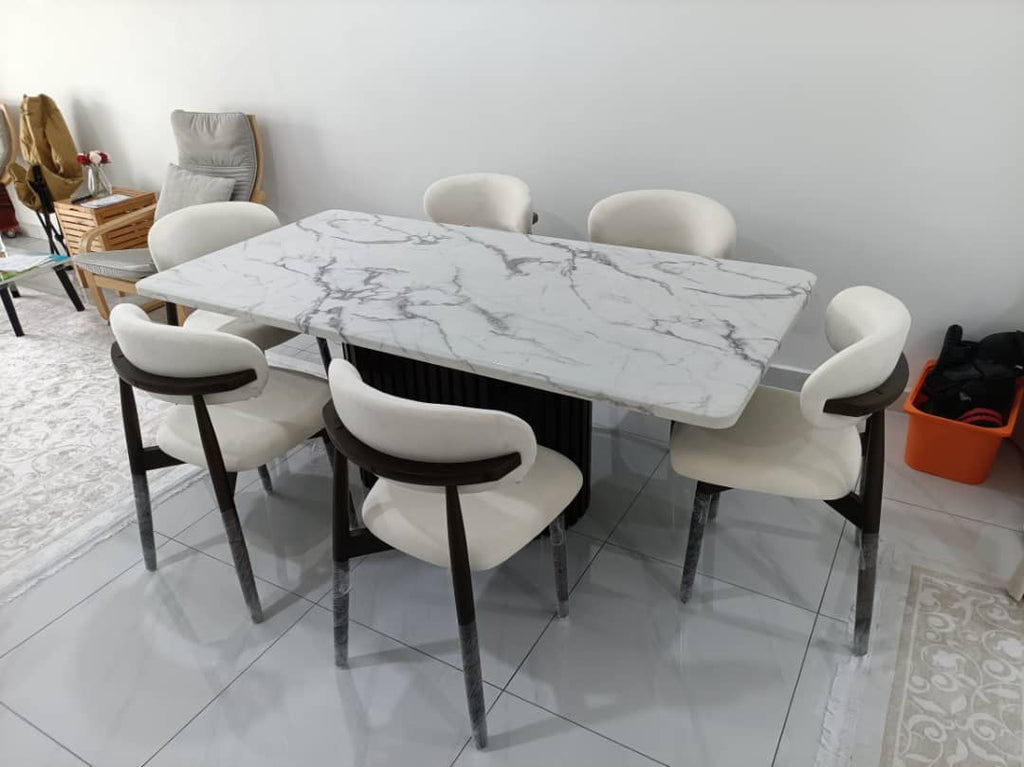 A modern 5-piece dining set featuring a rectangular white marble-patterned table and six matching chairs with cream upholstery and dark wood accents, shown in a home interior setting.