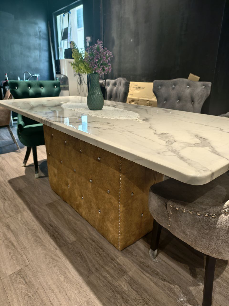 Marble dining table with tufted upholstered dining chairs in showroom