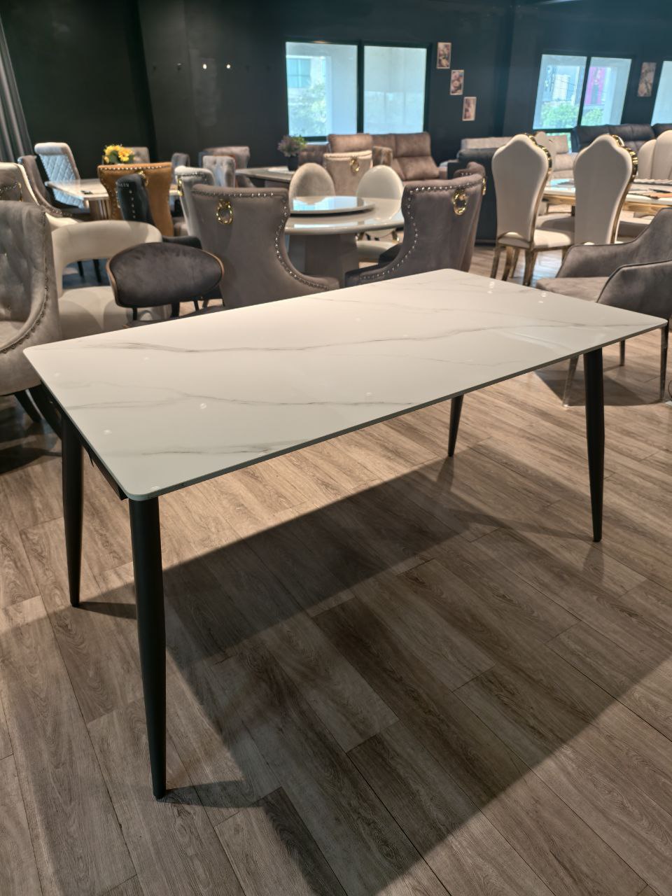 Rectangular marble-look dining table angled view with black tapered legs