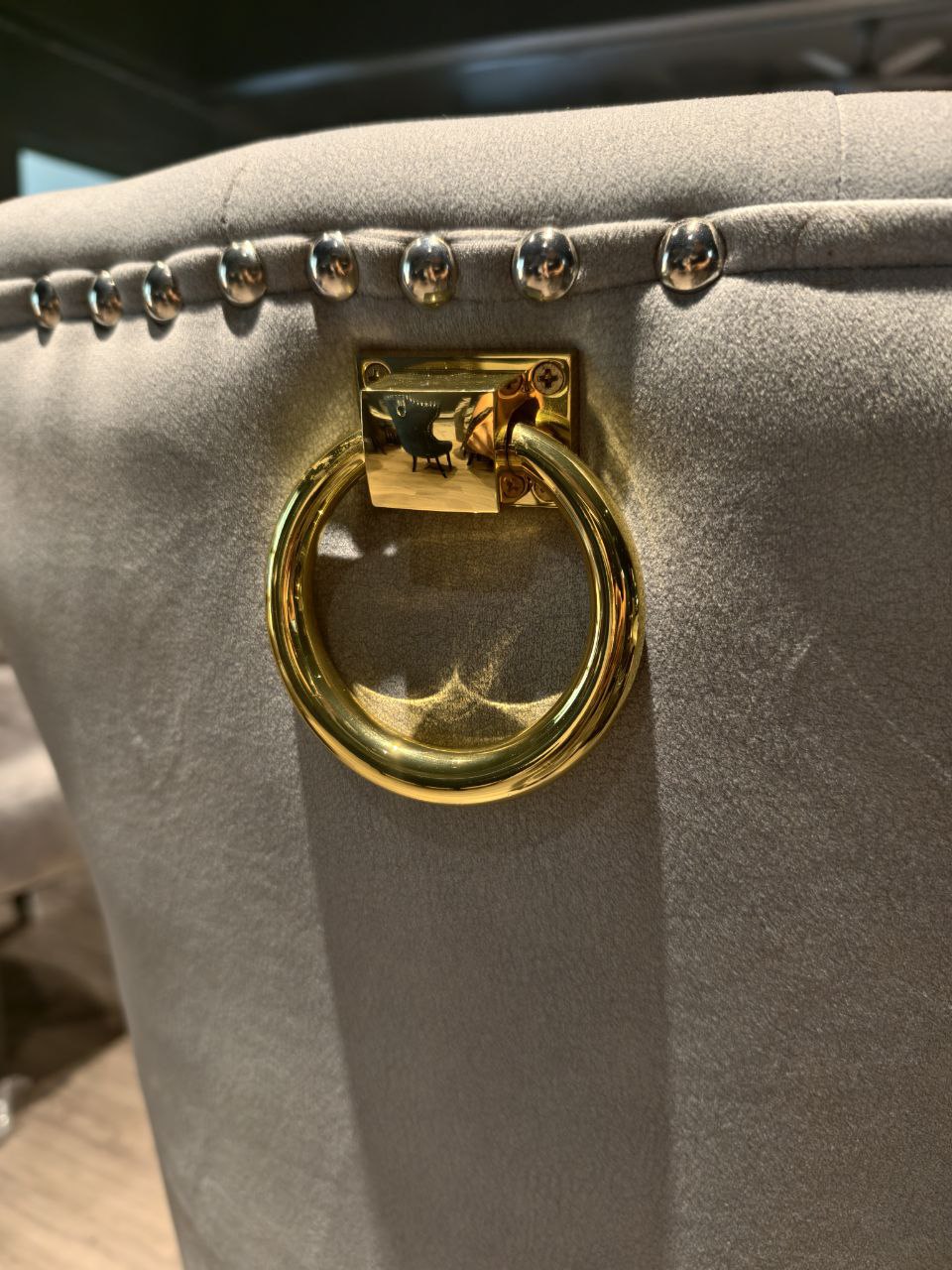 Close-up of gold ring handle on grey Butterfly dining chair back